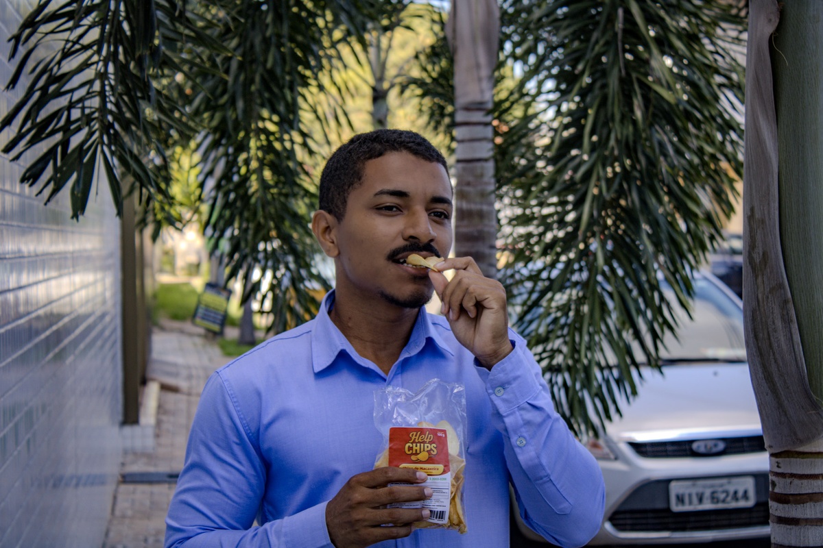 Consumidor degustando os chips de macaxeira diretamente do pacote